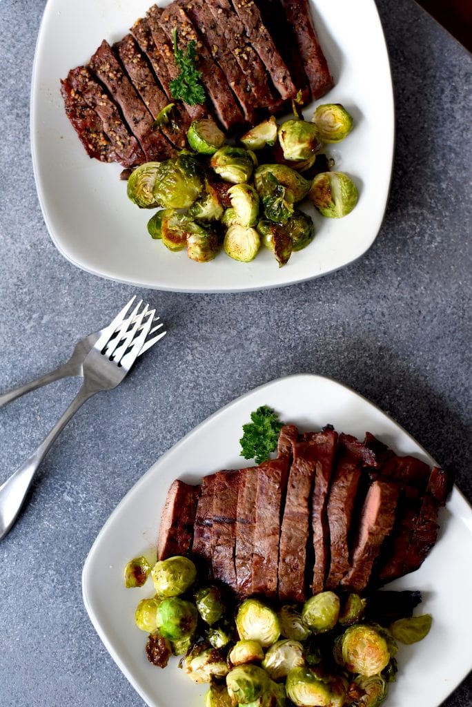 Brussels sprouts and steak on plates.