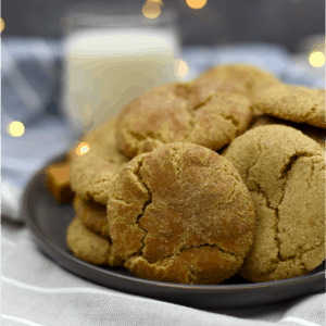 Caramel snickerdoodle cookies on a plate with glass of milk in the background