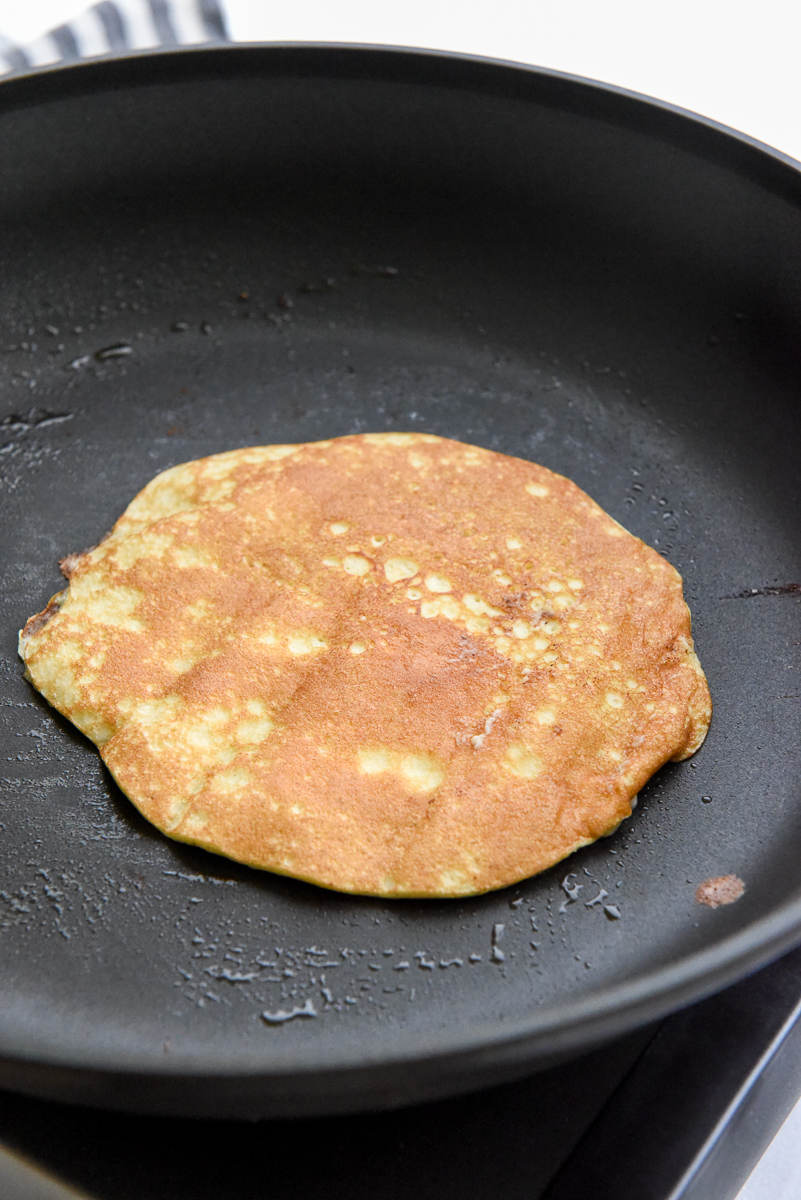Healthy Banana pancake on a frying pan after being flipped.